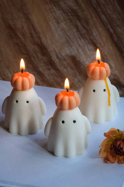 Handmade soy wax ghost candle wearing a small orange pumpkin hat