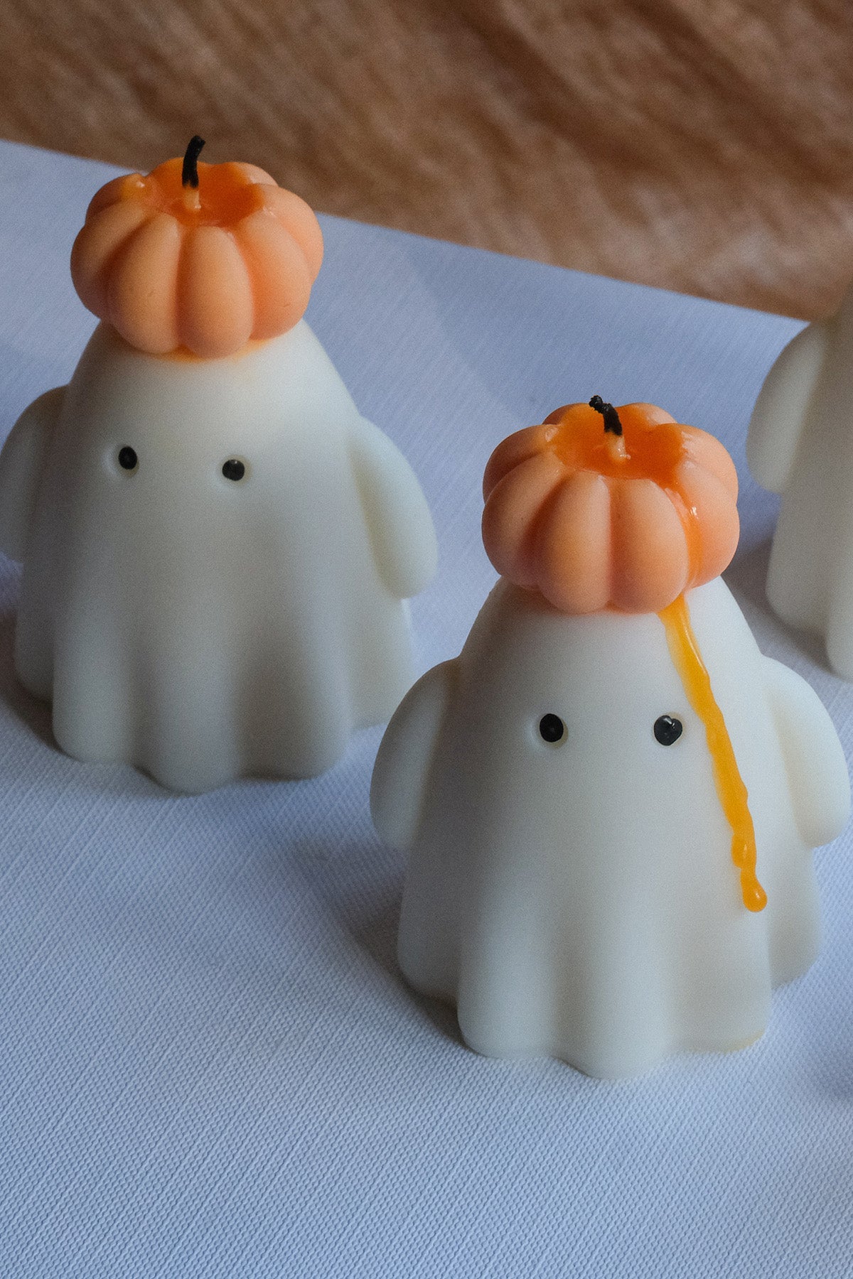 Handmade soy wax ghost candle wearing a small orange pumpkin hat