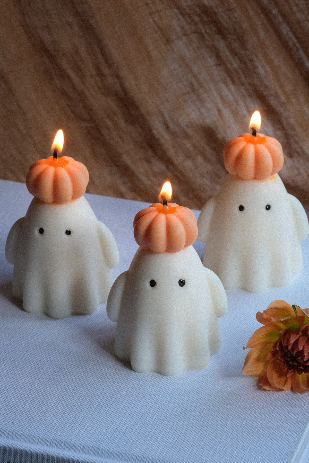 Handmade soy wax ghost candle wearing a small orange pumpkin hat